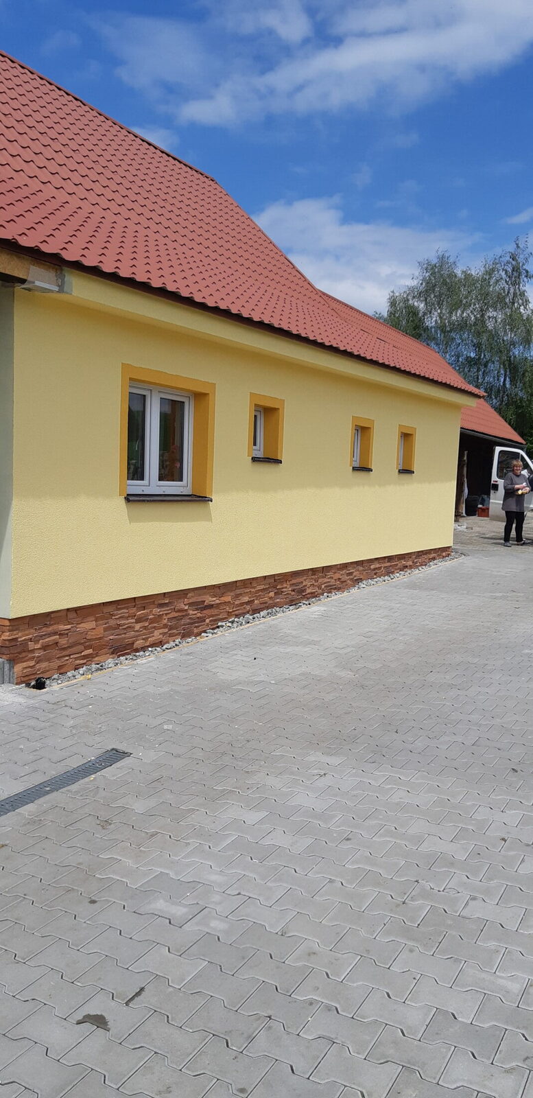 Zateplený dom so žltou fasádou a novou zámkovou dlažbou